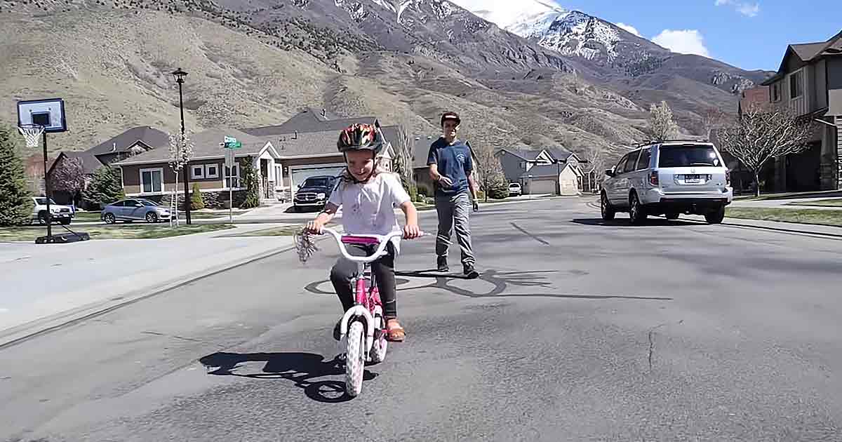 Brother teaches little sister to ride a bike