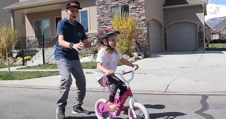 Brother teaches little sister to ride a bike